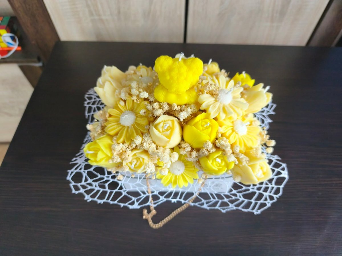 Vibrant yellow flower arrangement with roses, daisies, and babys breath on white lace fabric with pearl beading